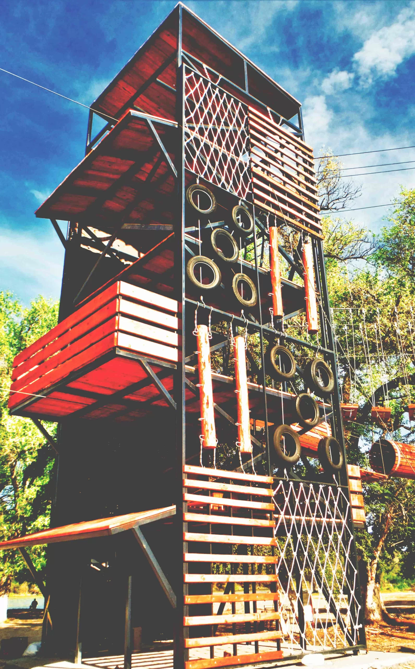 Ecoproparks. Foto de una emocionante torre de aventura en Ecoproparks, hecha de madera, metal, llantas, troncos y sogas, ofreciendo una atracción única para los entusiastas de la escalada y la naturaleza.